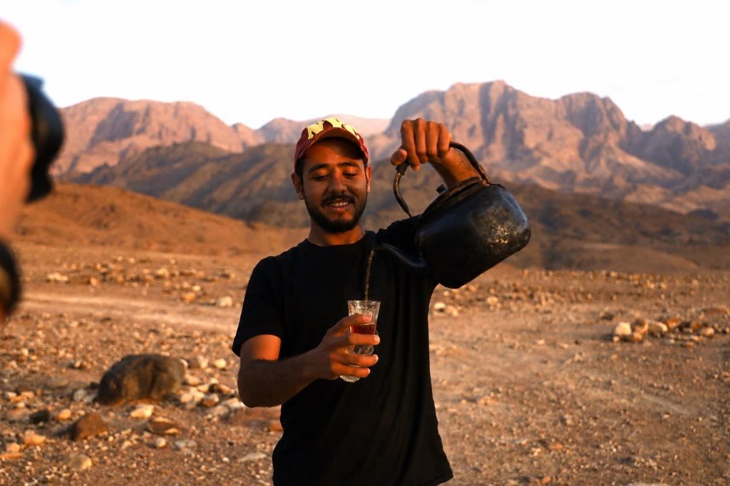 Local guide pouring traditional Bedouin tea on the trail