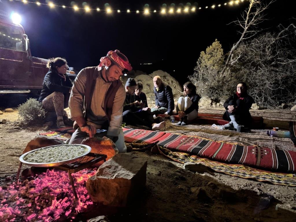 Bedouin chef cooking over glowing embers for guests at night